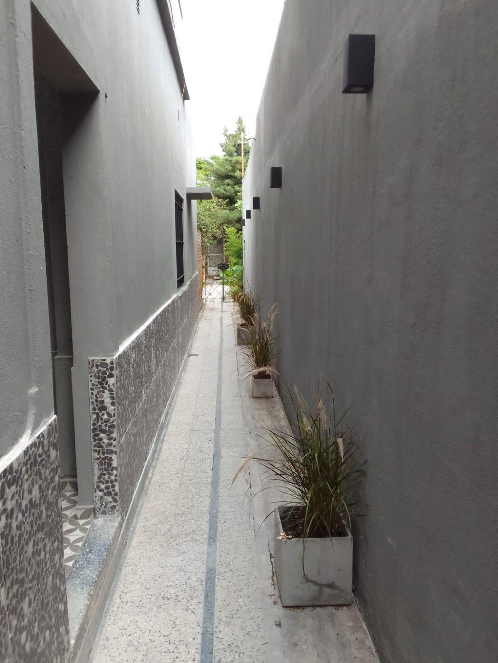 Pasillo estrecho moderno entre paredes grises con luces empotradas — proyecto Casa en Sarandi, por Arquitecto Guido Niccoli, en B1872 Sarandí